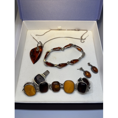 527 - FOUR SILVER AND AMBER ITEMS TO INCLUDE TWO BRACELETS, A PAIR OF EARRINGS AND A PENDANT ON A SILVER C... 