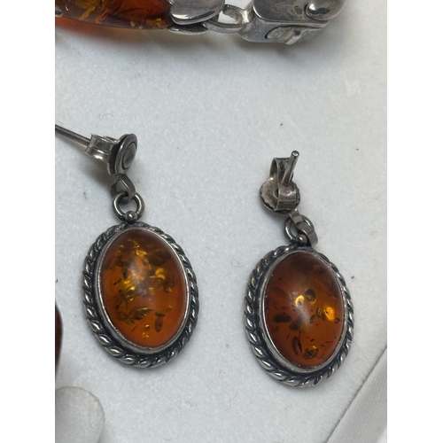 527 - FOUR SILVER AND AMBER ITEMS TO INCLUDE TWO BRACELETS, A PAIR OF EARRINGS AND A PENDANT ON A SILVER C... 