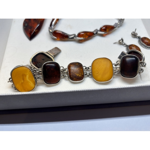 527 - FOUR SILVER AND AMBER ITEMS TO INCLUDE TWO BRACELETS, A PAIR OF EARRINGS AND A PENDANT ON A SILVER C... 