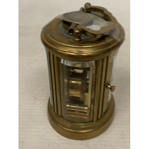 31 - A SMALL OVAL BRASS CARRIAGE CLOCK WITH GLASS ESCAPEMENT AND KEY