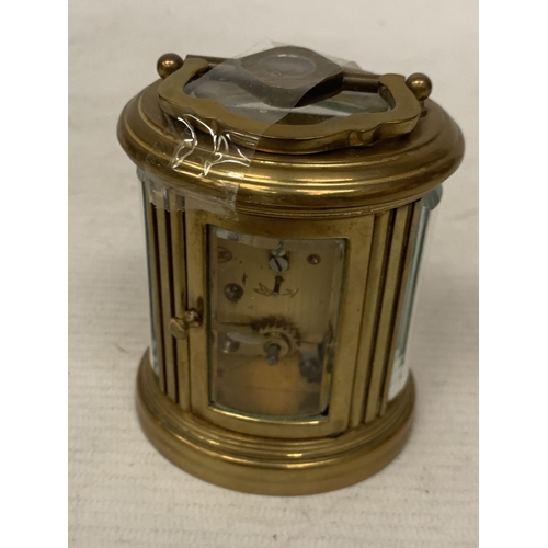 31 - A SMALL OVAL BRASS CARRIAGE CLOCK WITH GLASS ESCAPEMENT AND KEY
