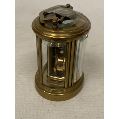31 - A SMALL OVAL BRASS CARRIAGE CLOCK WITH GLASS ESCAPEMENT AND KEY