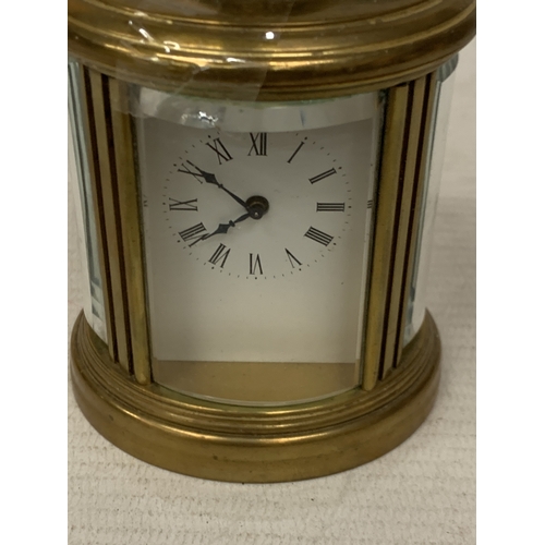 31 - A SMALL OVAL BRASS CARRIAGE CLOCK WITH GLASS ESCAPEMENT AND KEY