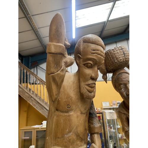 68 - TWO LARGE WOODEN CARVED FIGURES OF A BLACKSMITH AND A LADY WITH A BASKET ON HER HEAD, HEIGHT 68CM