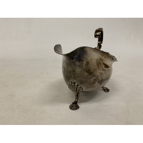 1 - A 1930'S HALLMARKED BIRMINGHAM SILVER SAUCE BOAT WITH A WAVY EDGE RIM AND RAISED ON THREE ORNATE FEE... 