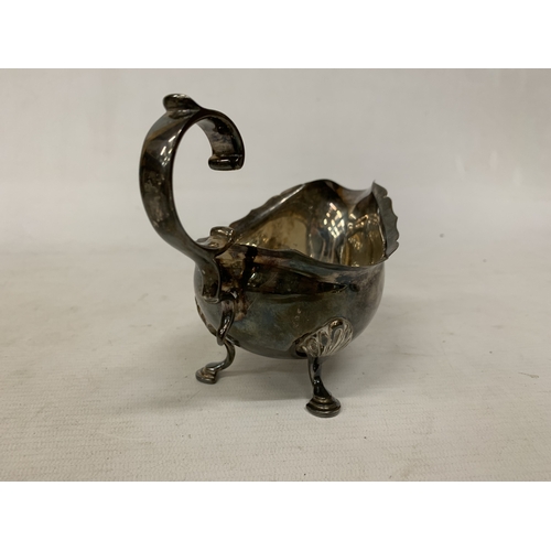 1 - A 1930'S HALLMARKED BIRMINGHAM SILVER SAUCE BOAT WITH A WAVY EDGE RIM AND RAISED ON THREE ORNATE FEE... 