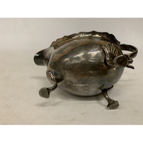 1 - A 1930'S HALLMARKED BIRMINGHAM SILVER SAUCE BOAT WITH A WAVY EDGE RIM AND RAISED ON THREE ORNATE FEE... 