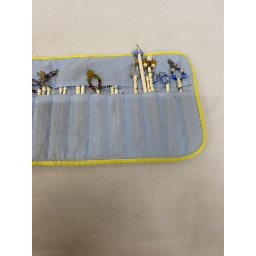 23 - A COLLECTION (APPROX 36) OF BONE LACE MAKING BOBBINS WITH CHARMS AND SPANGLES IN A POUCH