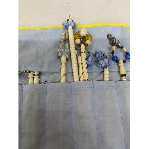 23 - A COLLECTION (APPROX 36) OF BONE LACE MAKING BOBBINS WITH CHARMS AND SPANGLES IN A POUCH