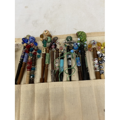55 - A COLLECTION OF 34 LACE MAKING BOBBINS, MANY WITH ENAMEL DECORATION, CHARMS AND SPANGLES IN A CLOTH ... 