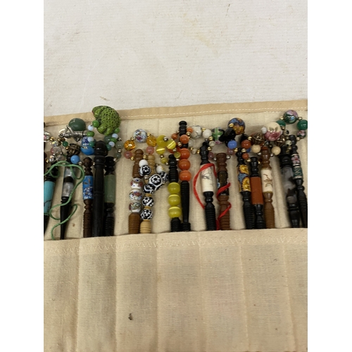 55 - A COLLECTION OF 34 LACE MAKING BOBBINS, MANY WITH ENAMEL DECORATION, CHARMS AND SPANGLES IN A CLOTH ... 