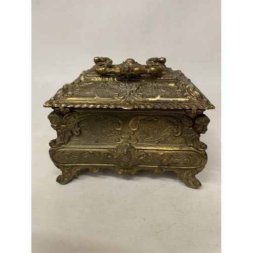 11 - A GILDED CASKET WITH REPOUSSE FLORAL AND SCROLL DECORATION WITH CHERUB ACCENTS IN THE CORNERS WITH K... 