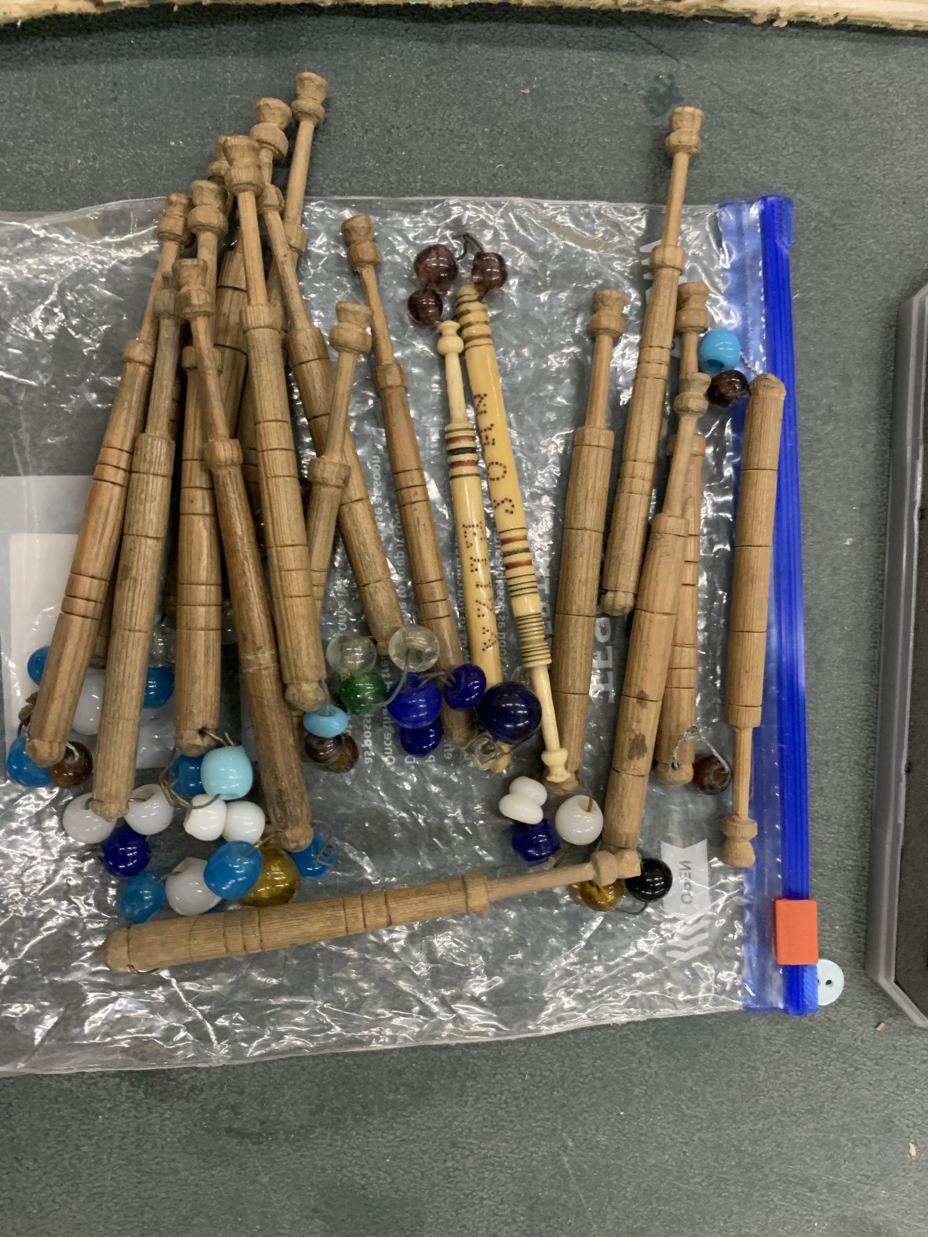 A COLLECTION OF WOODEN AND CARVED BONE BOBBINS WITH GLASS SPANGLES
