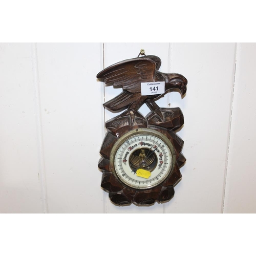 141 - A CARVED BLACK FOREST STYLE BAROMETER WITH BIRD FINIAL TO TOP