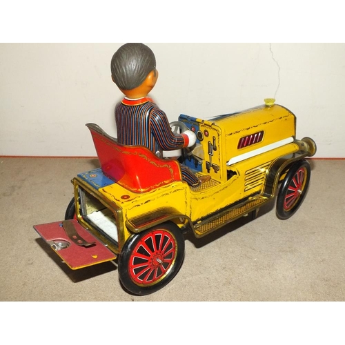 232 - A VINTAGE BATTERY OPERATED TIN PLATE TOY MAN IN A CLASSIC CAR