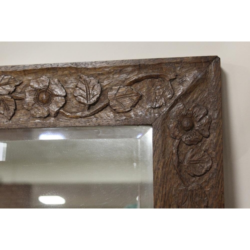 29 - AN OAK FRAMED MIRROR WITH FLORAL CARVED DETAIL - OVERALL SIZE 81 CM BY 59 CM