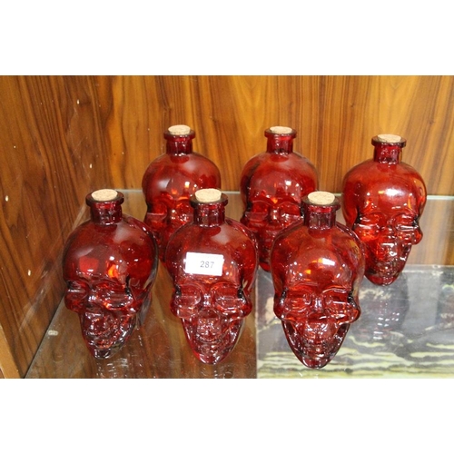 287 - SIX RED GLASS SKULL DECANTERS