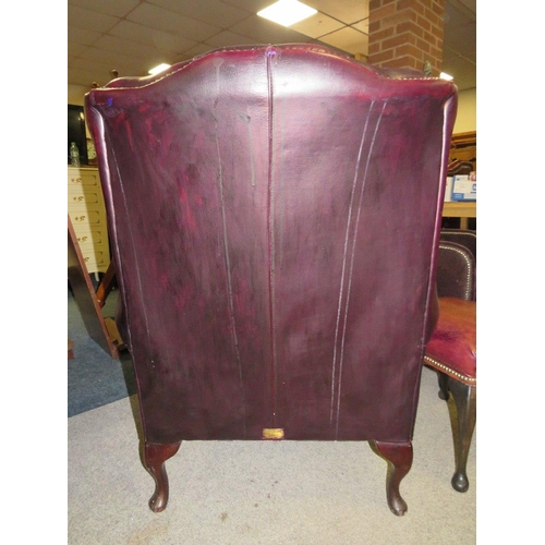 735 - AN OXBLOOD RED LEATHER WINGBACK ARMCHAIR BY MARTIN BARNES LONDON TOGETHER WITH A STOOL