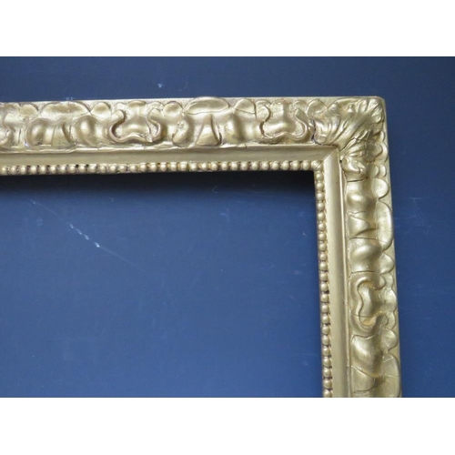 102 - A LATE 19TH / EARLY 20TH CENTURY DECORATIVE GOLD FRAME, with bead design to inner edge and plant des... 