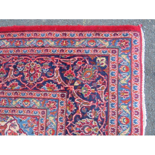 886 - A LARGE RED / BLUE GROUND CARPET, APPROX 389 X 297 CM - WEAR THROUGHOUT