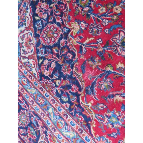886 - A LARGE RED / BLUE GROUND CARPET, APPROX 389 X 297 CM - WEAR THROUGHOUT