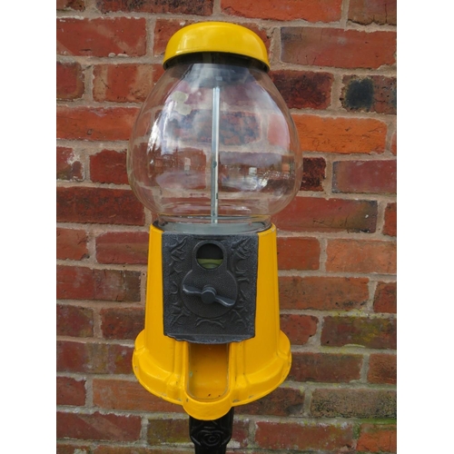 521 - A VINTAGE AMERICAN GUMBALL MACHINE ON CAST IRON BASE, with yellow painted alloy body and glass globe... 