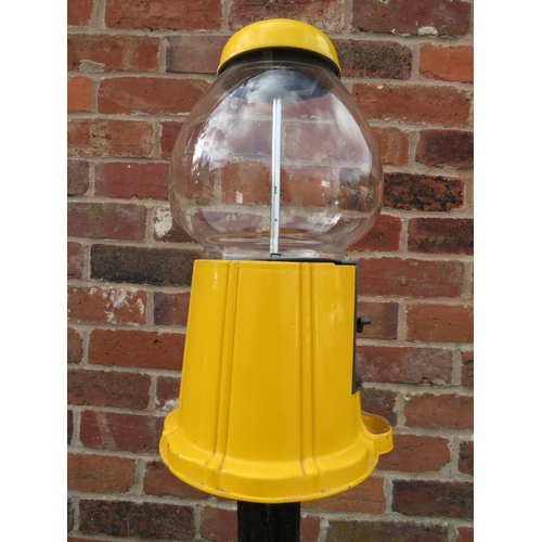 521 - A VINTAGE AMERICAN GUMBALL MACHINE ON CAST IRON BASE, with yellow painted alloy body and glass globe... 