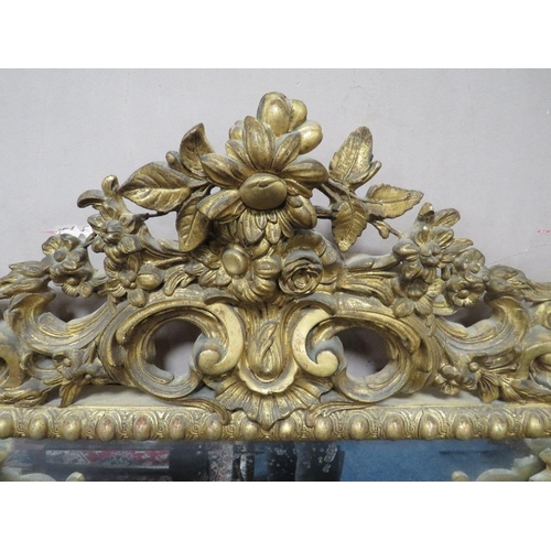 566 - AN EARLY 19TH CENTURY GILT AND COMPOSITION WALL MIRROR, the scrolling Rococo style surmount above tw... 