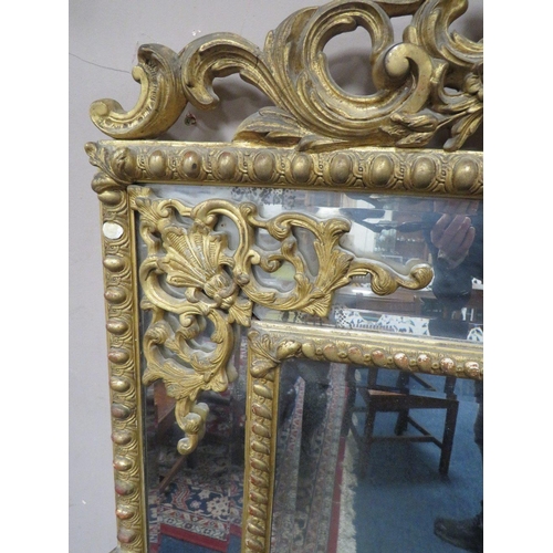 566 - AN EARLY 19TH CENTURY GILT AND COMPOSITION WALL MIRROR, the scrolling Rococo style surmount above tw... 