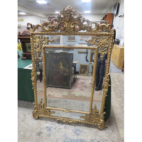 566 - AN EARLY 19TH CENTURY GILT AND COMPOSITION WALL MIRROR, the scrolling Rococo style surmount above tw... 