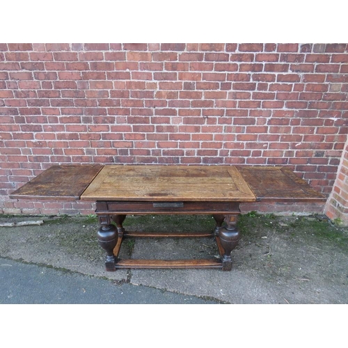 604 - AN ANTIQUE OAK DRAWLEAF REFECTORY TABLE, raised on four baluster supports united by well-worn stretc... 