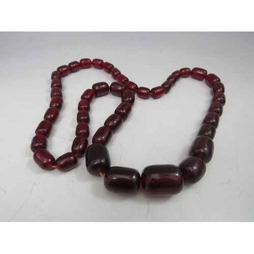 275 - A VINTAGE CHERRY AMBER GRADUATED BEAD NECKLACE, single strand, no fastener, central bead W 2.5 cm, a... 