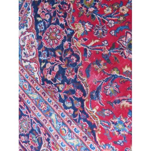 881 - A LARGE RED / BLUE GROUND CARPET, APPROX 389 X 297 CM - WEAR THROUGHOUT