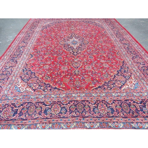 881 - A LARGE RED / BLUE GROUND CARPET, APPROX 389 X 297 CM - WEAR THROUGHOUT