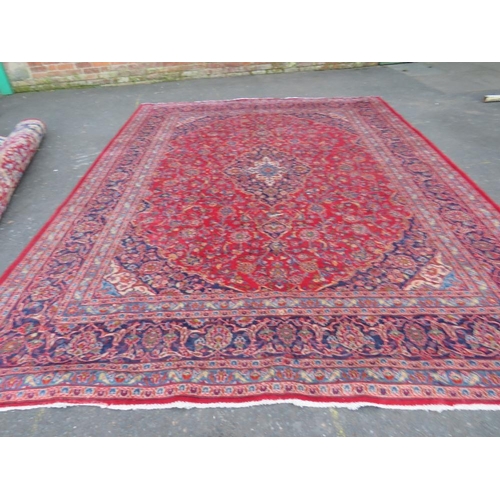 881 - A LARGE RED / BLUE GROUND CARPET, APPROX 389 X 297 CM - WEAR THROUGHOUT