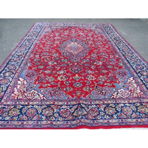 882 - A LARGE CARPET WITH RED CENTRAL GROUND AND BLUE BORDER, APPROX 360 X 270 CM - WEAR THROUGHOUT