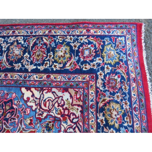 882 - A LARGE CARPET WITH RED CENTRAL GROUND AND BLUE BORDER, APPROX 360 X 270 CM - WEAR THROUGHOUT