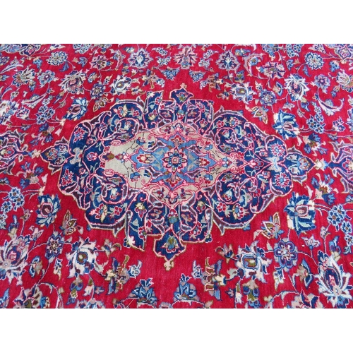 882 - A LARGE CARPET WITH RED CENTRAL GROUND AND BLUE BORDER, APPROX 360 X 270 CM - WEAR THROUGHOUT