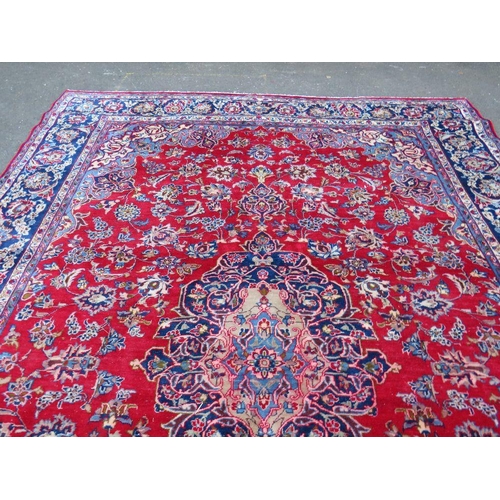 882 - A LARGE CARPET WITH RED CENTRAL GROUND AND BLUE BORDER, APPROX 360 X 270 CM - WEAR THROUGHOUT