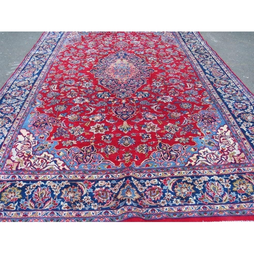 882 - A LARGE CARPET WITH RED CENTRAL GROUND AND BLUE BORDER, APPROX 360 X 270 CM - WEAR THROUGHOUT