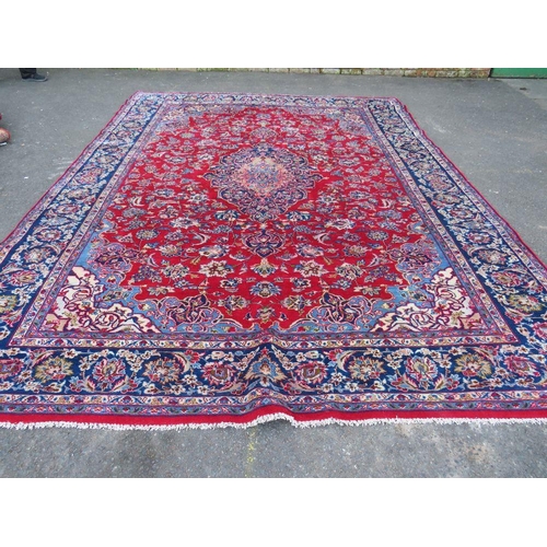 882 - A LARGE CARPET WITH RED CENTRAL GROUND AND BLUE BORDER, APPROX 360 X 270 CM - WEAR THROUGHOUT