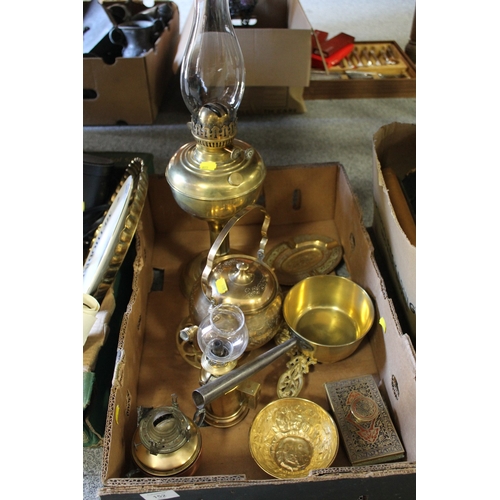 152 - A TRAY OF ASSORTED BRASSWARE TO INCLUDE TWO OIL LAMPS, SAUCEPAN, TRIVETS ETC