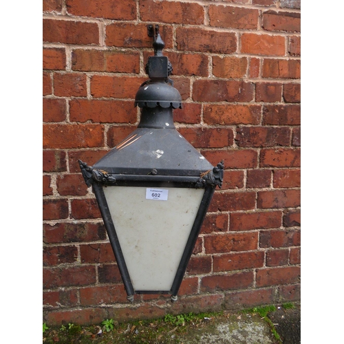 602 - A SMALL EXTERNAL LANTERN WITH COPPER TOP, HAVING ORNATE CAST WALL MOUNTING BRACKET