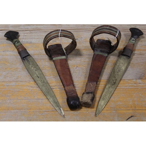 348 - A PAIR OF EASTERN DAGGERS IN LEATHER SHEATHS WITH ARMBANDS