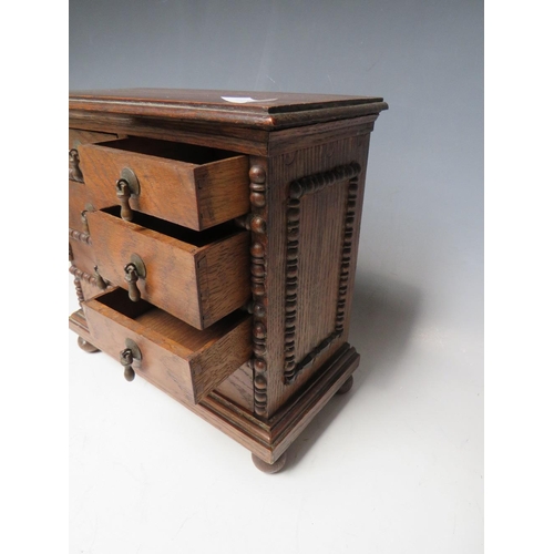 511 - A VICTORIAN MINIATURE OAK COLLECTORS CHEST OF EIGHT DRAWERS, with beadwork detail, raised on bun fee... 