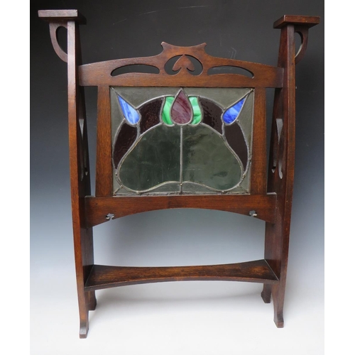 608 - AN EARLY 20TH CENTURY OAK GLAZED ART NOUVEAU FIRE SCREEN, the glass panel with coloured and leaded s... 