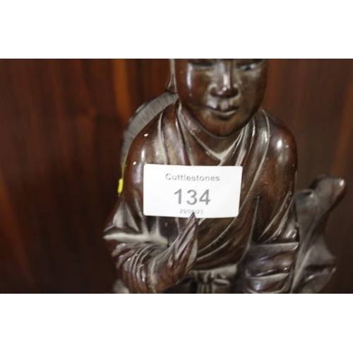 134 - A CARVED ORIENTAL HARDWOOD FIGURE OF A YOUNG MAN WITH DOG