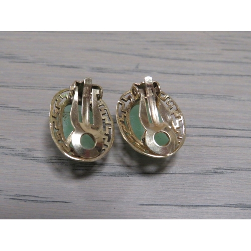 192 - A PAIR OF UNMARKED YELLOW METAL EARRINGS SET WITH CABOCHON POLISHED GREEN STONES, with clip on faste... 