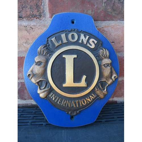 255 - A LIONS INTERNATIONAL CLUB PLAQUE MOUNTED ON WOODEN BACK BOARD