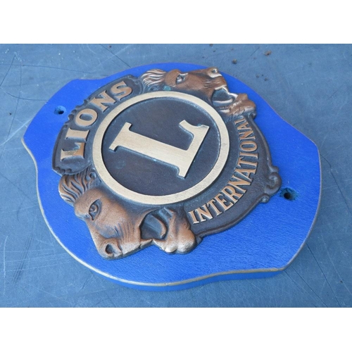 255 - A LIONS INTERNATIONAL CLUB PLAQUE MOUNTED ON WOODEN BACK BOARD